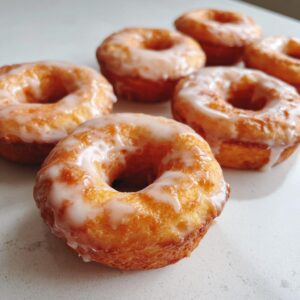 Several glazed air fryer donuts with biscuit dough, golden brown and topped with a sweet white glaze.
