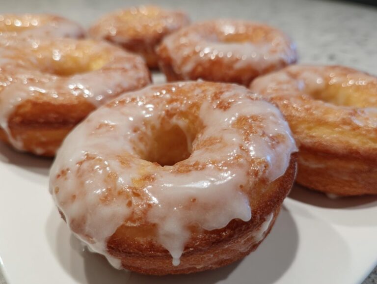 Close-up of glazed air fryer donuts made with biscuit dough, arranged on a white plate.