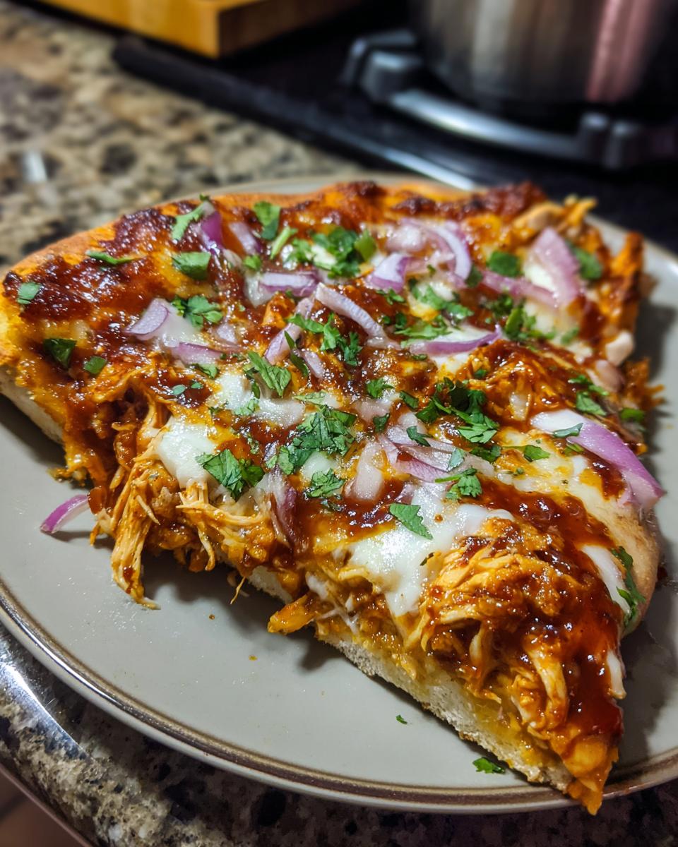 A delicious slice of BBQ chicken pizza topped with red onion, cilantro, and melted cheese.
