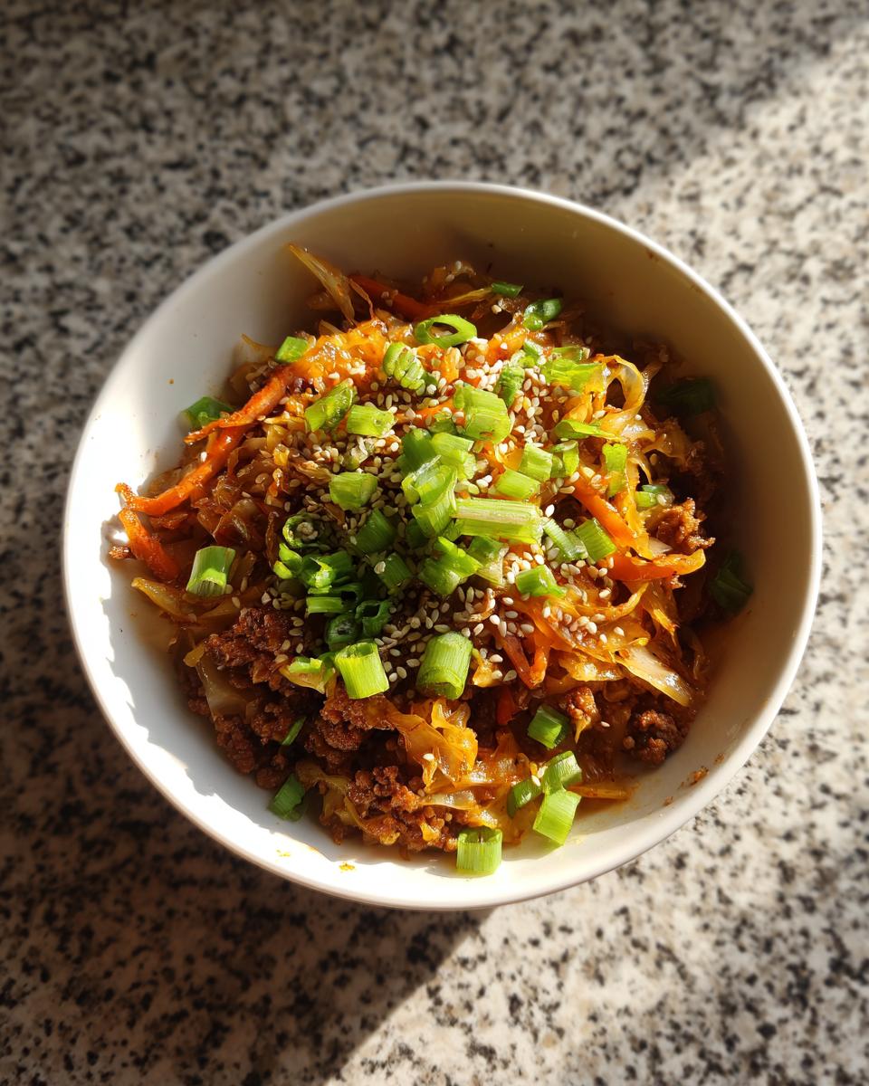 Overhead shot of a bowl of Egg roll in a bowl, garnished with sesame seeds and chopped green onions.