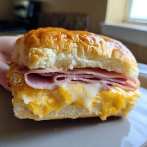 Close-up of a ham and cheese sliders featuring melted cheese and a golden bun.