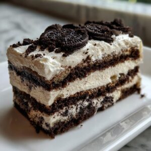 A delicious slice of Oreo icebox cake featuring layers of cookies and cream, topped with Oreo cookies.