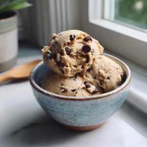 Two scoops of safe edible cookie dough with chocolate chips in a blue ceramic bowl.