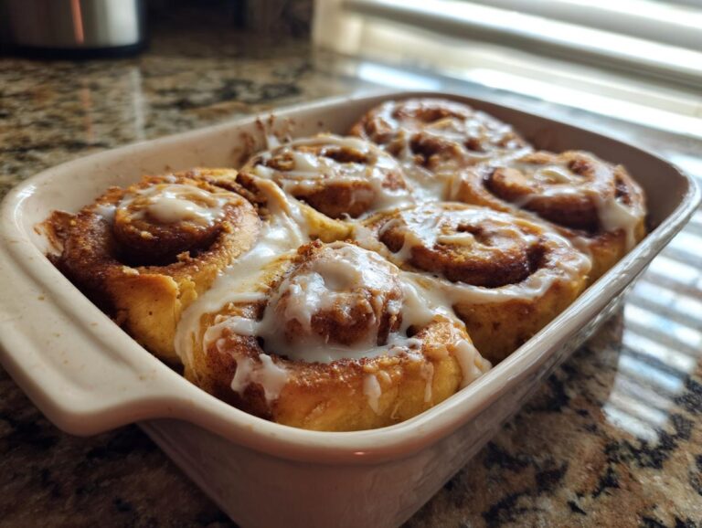 Freshly baked TikTok cinnamon rolls with icing in a white baking dish, ready to eat.