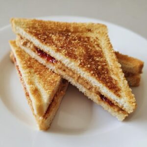 Two Homemade Uncrustables sandwiches, cut into triangles, showing peanut butter and jelly filling.