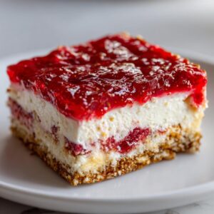A single slice of Strawberry Pretzel Salad on a white plate, showcasing the pretzel crust, cream cheese layer, and strawberry topping.