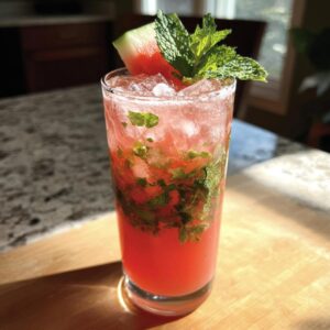 A vibrant Watermelon Mojito in a tall glass, garnished with watermelon and fresh mint.