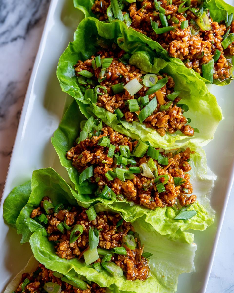 Close-up of Chicken Lettuce Wraps Copycat PF Chang's, filled with seasoned ground chicken and topped with chopped green onions.