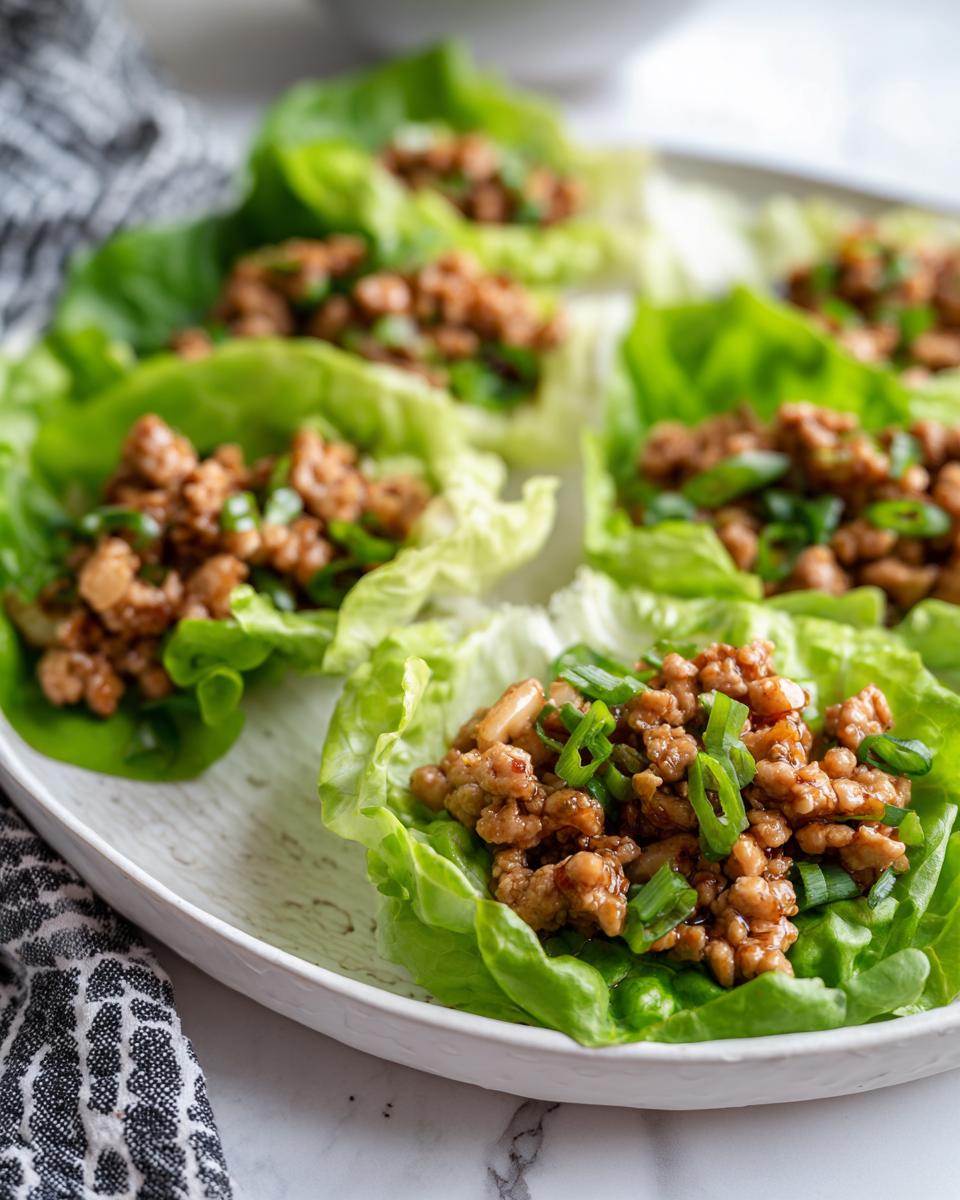 Close-up of delicious Chicken Lettuce Wraps Copycat PF Chang's, filled with seasoned ground chicken and topped with green onions.