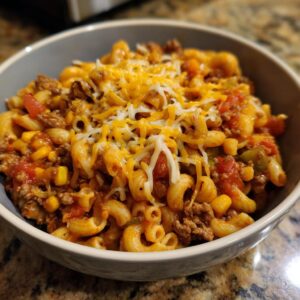 A close-up of a bowl of One-Pot Taco Pasta topped with melted cheddar and Monterey Jack cheese.