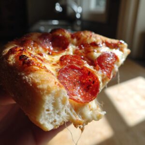 A close-up shot of a slice of pepperoni pizza, showing melted cheese and crispy pepperoni.