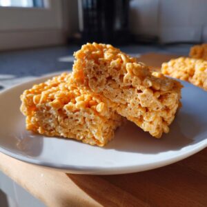 Close-up of two Pumpkin Rice Krispie Treats on a white plate, showing their chewy texture.