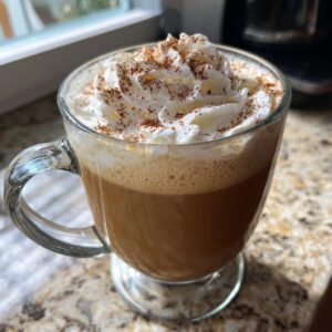 A close-up of a warm Pumpkin Spice Latte topped with whipped cream and a sprinkle of cinnamon.
