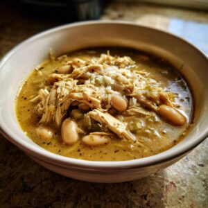 A close-up of a bowl of delicious White Chicken Chili, filled with shredded chicken, white beans, and broth.