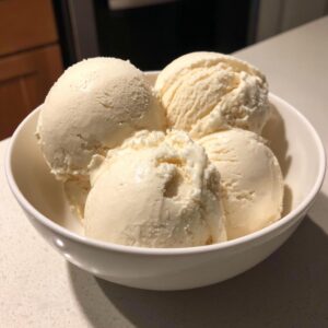Close-up of four generous scoops of creamy vanilla protein ice cream in a white bowl.