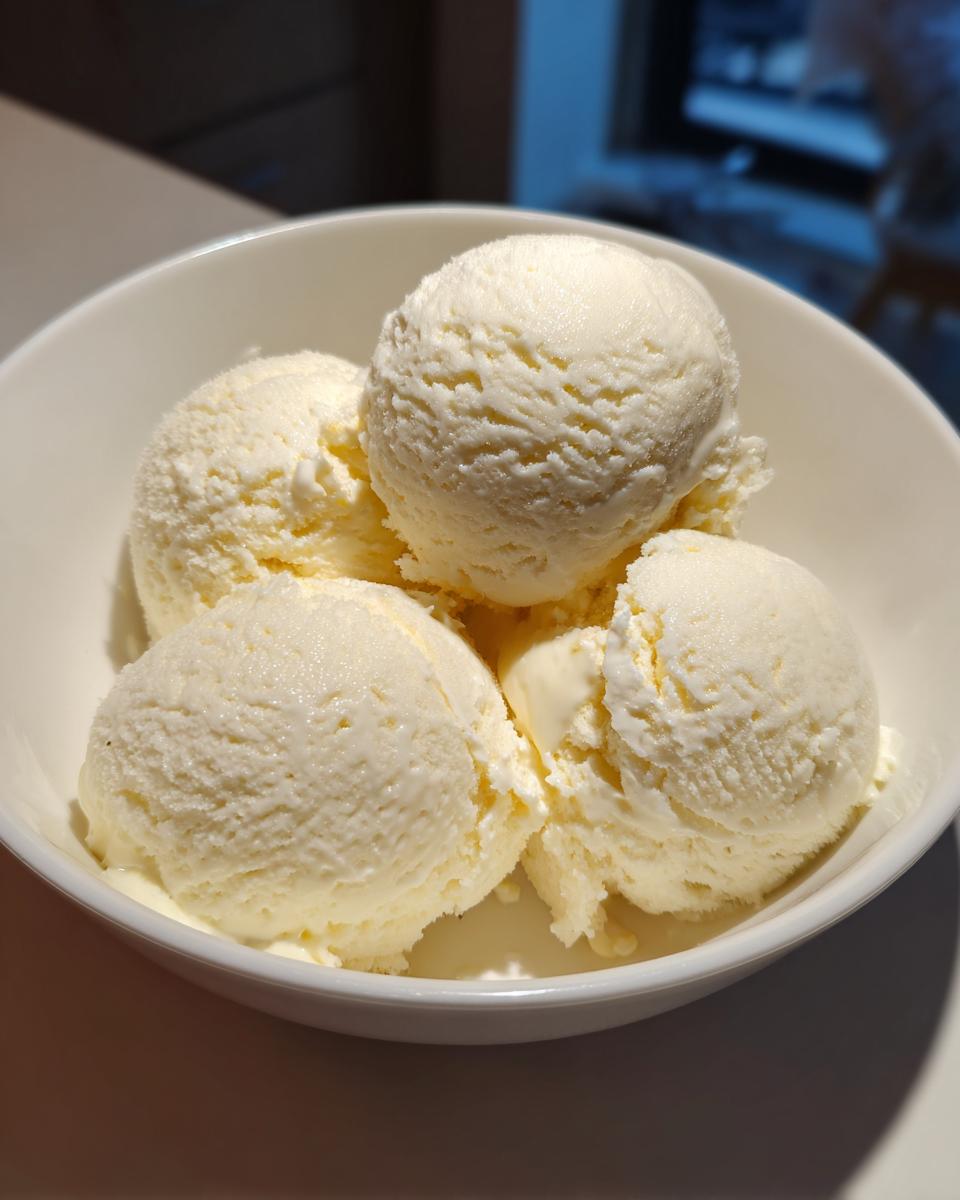 Four scoops of creamy, vanilla-colored protein ice cream served in a white bowl.