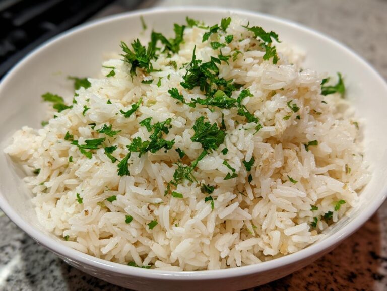 Close-up of a white bowl filled with fluffy, white rice pilaf garnished generously with chopped fresh parsley.