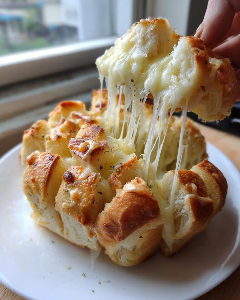 A hand pulling apart a piece of baked cheese bread, showing long, gooey strings of melted cheese.