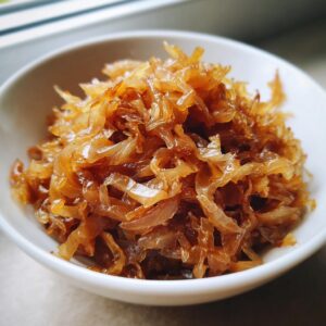 Close-up of deeply browned and sweet caramelized onions piled high in a small white bowl.