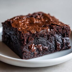 Close-up of a single, rich, fudgy brownies square showing a shiny top crust and melted chocolate chips.