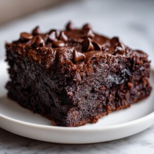 Close-up of a rich, dark chocolate sweet potato brownies slice topped with melted chocolate chips.