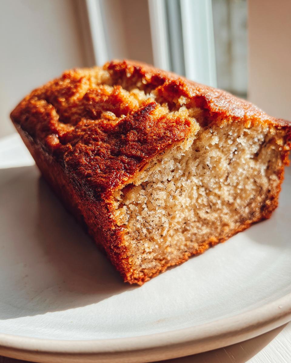 Close-up of a slice of moist sugar free banana bread showing a golden brown crust and speckled interior.