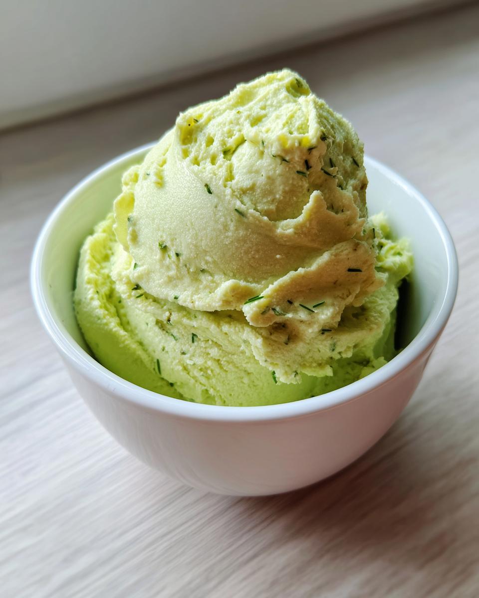 A generous scoop of bright green dill pickle dip, flecked with herbs, served in a white bowl.