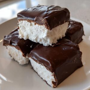 A stack of homemade cool whip candy squares featuring a thick, fluffy white center coated in rich dark chocolate.
