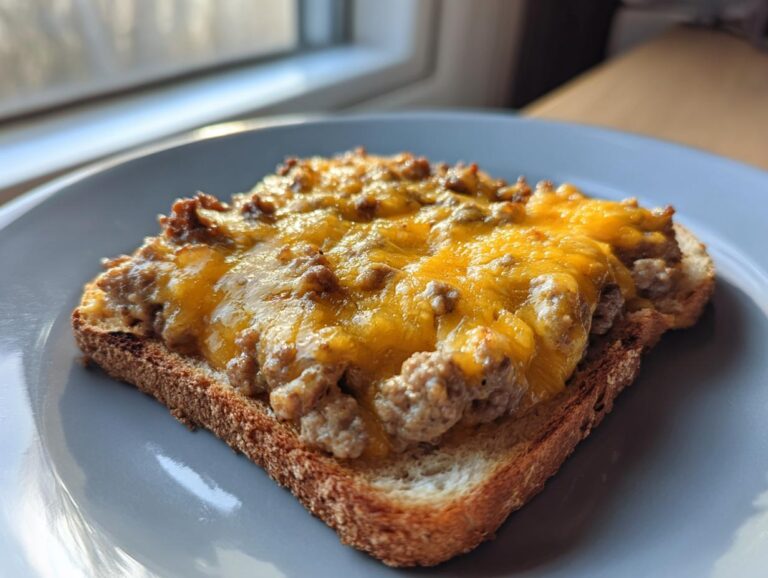 Close-up of a single piece of toast topped with the savory, cheesy mixture from the hanky panky recipe.