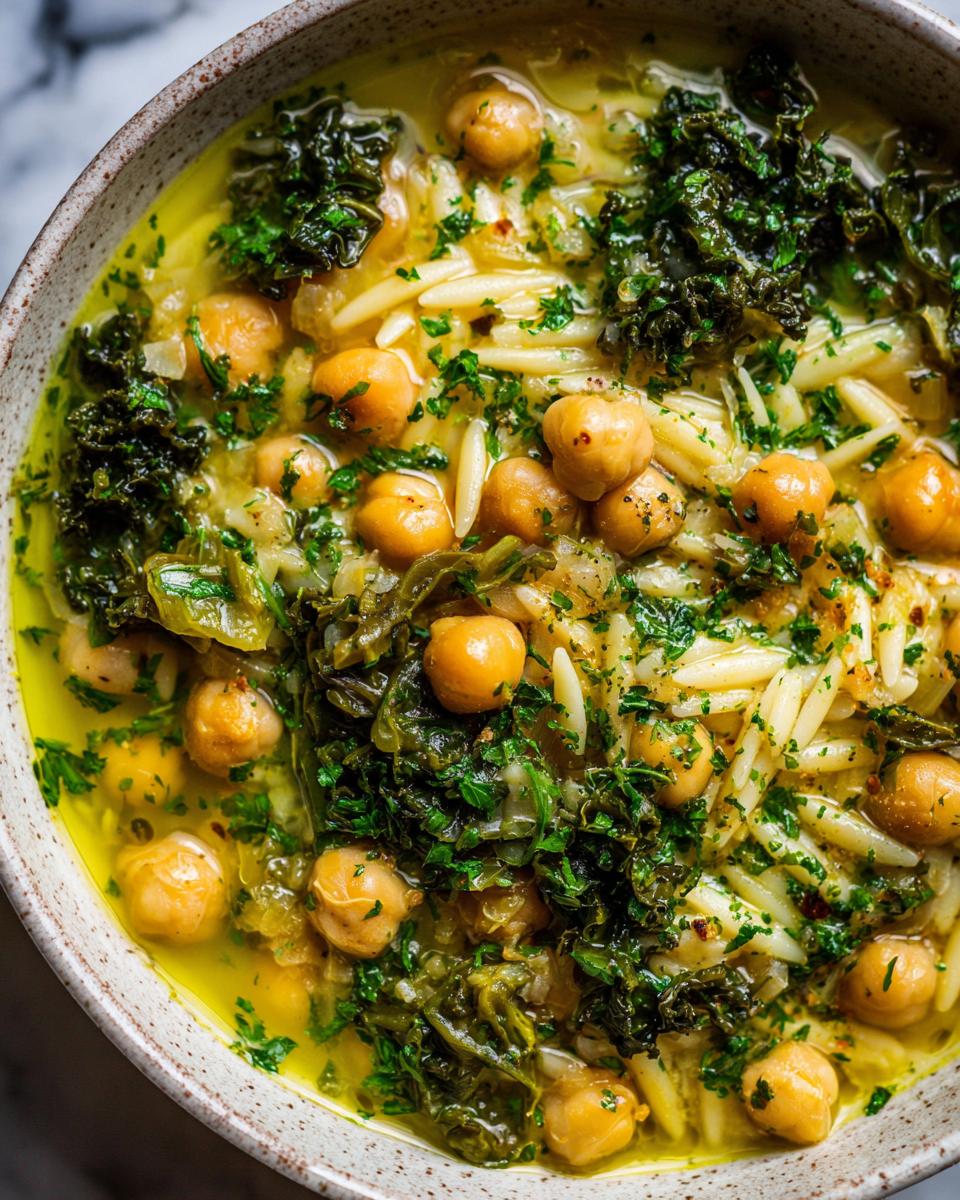 Close-up overhead shot of amazing greek chickpea soup featuring chickpeas, orzo pasta, and dark leafy greens.
