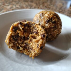 Close-up of two chocolate chip protein balls, one cut in half showing the texture of oats and chips.