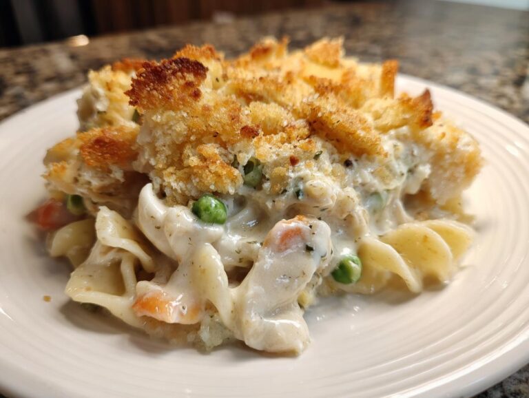 Close-up of a serving of creamy chicken noodle casserole topped with golden, crunchy breadcrumbs.