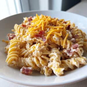 Close-up of a bowl of creamy ranch pasta salad made with rotini pasta, bacon bits, and shredded cheddar cheese.