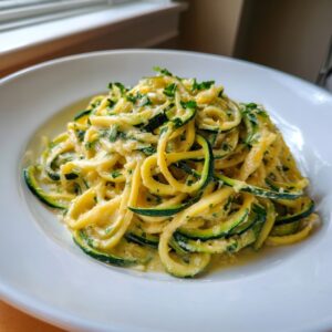 A close-up of creamy, sauced zucchini noodles topped with fresh parsley served in a white bowl.