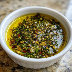 Close-up of a flavorful bread dip mixture of herbs, spices, and nuts submerged in olive oil.