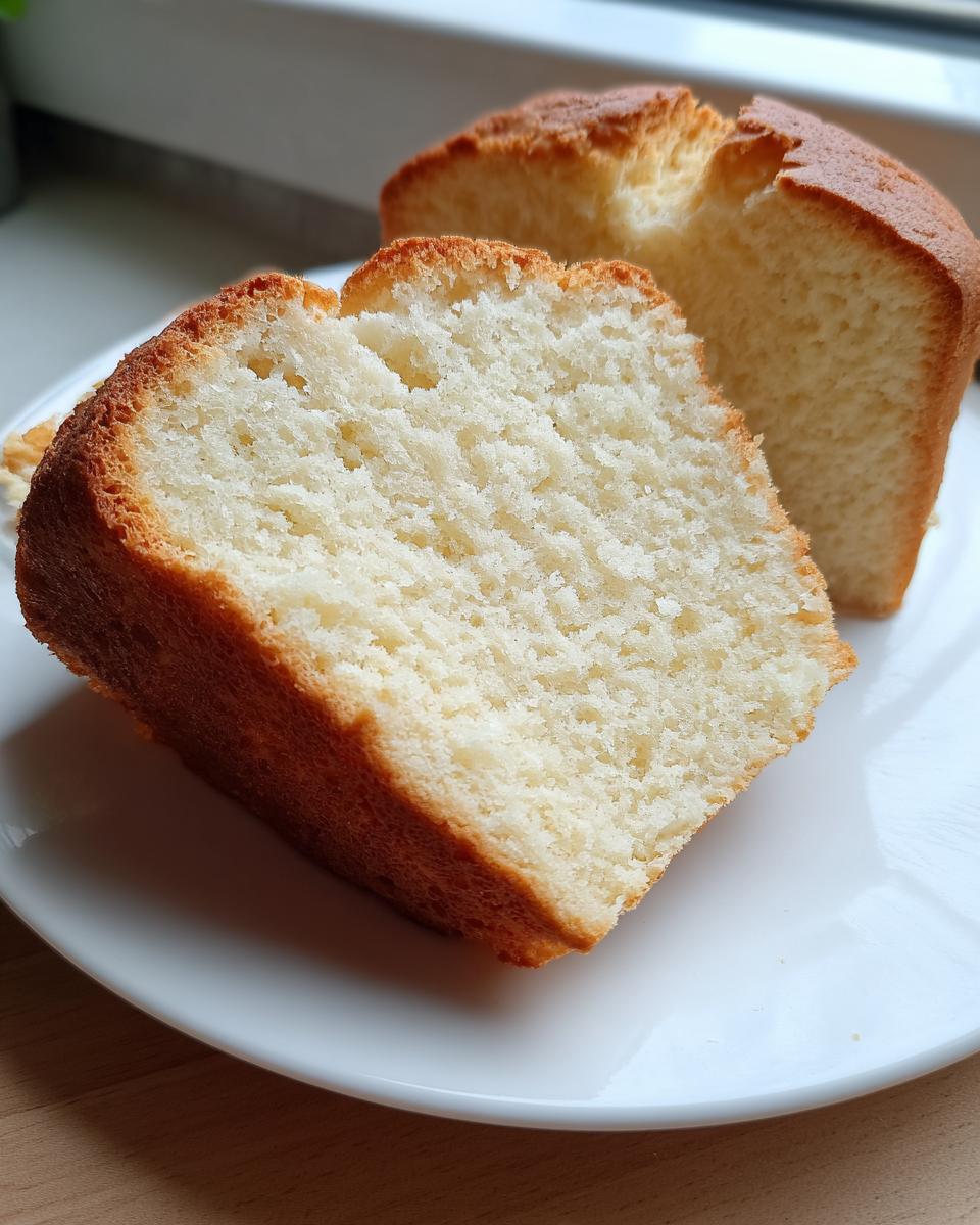 Close-up of a thick slice of fluffy cottage cheese bread showing its soft white interior and golden-brown crust.